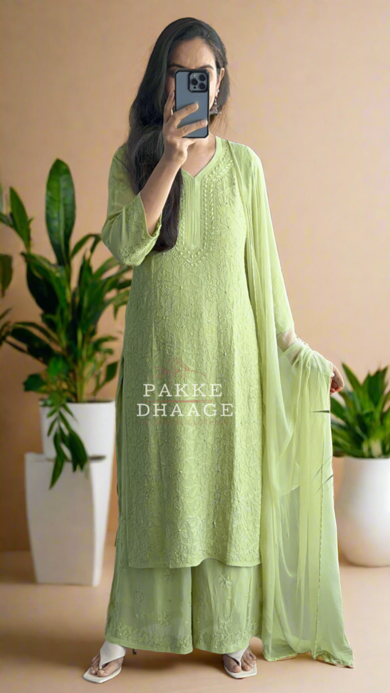 Person wearing a light green traditional outfit standing in front of a mirror.