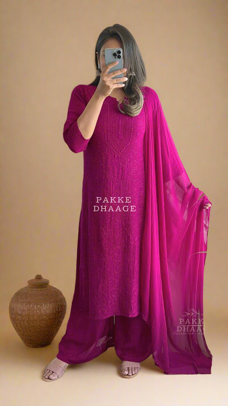 Person wearing a bright wine coloured traditional chikankari kurta set, with matching dupatta, standing in front of a mirror.