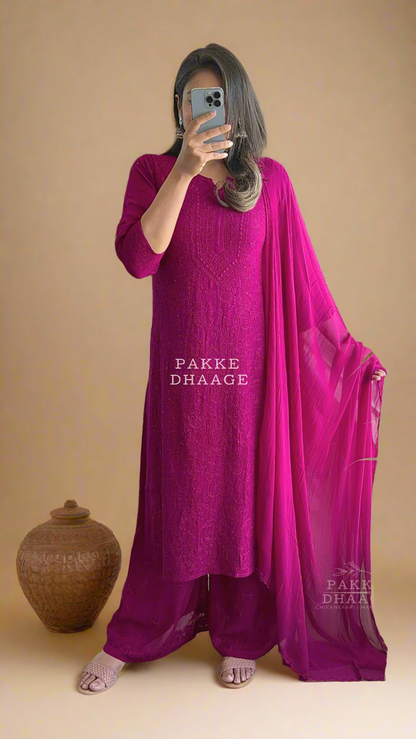 Person wearing a bright wine coloured traditional chikankari kurta set, with matching dupatta, standing in front of a mirror.