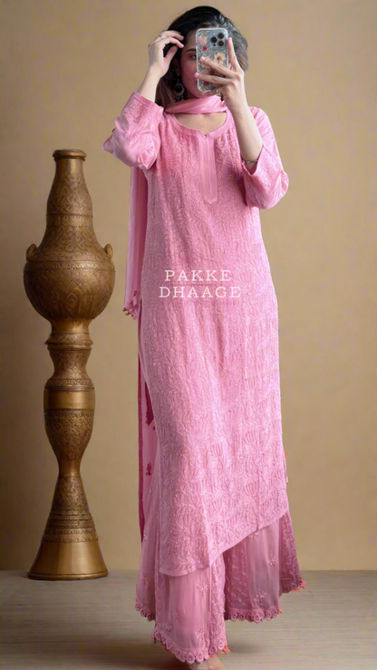 Person wearing a pink chikankari hand embroidered, in a warm lit room.