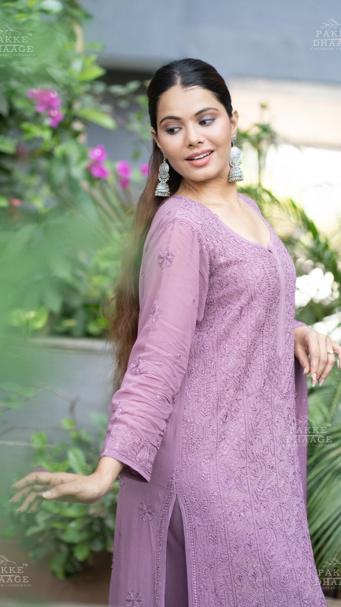 Woman wearing a plum chikankari suit with intricate embroidery in an outdoor setting