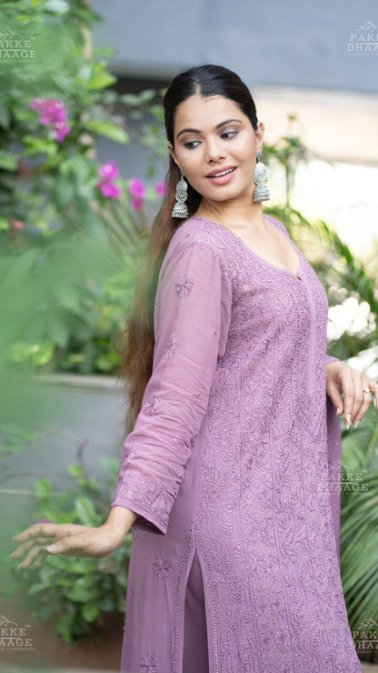 Woman wearing a plum chikankari suit with intricate embroidery in an outdoor setting