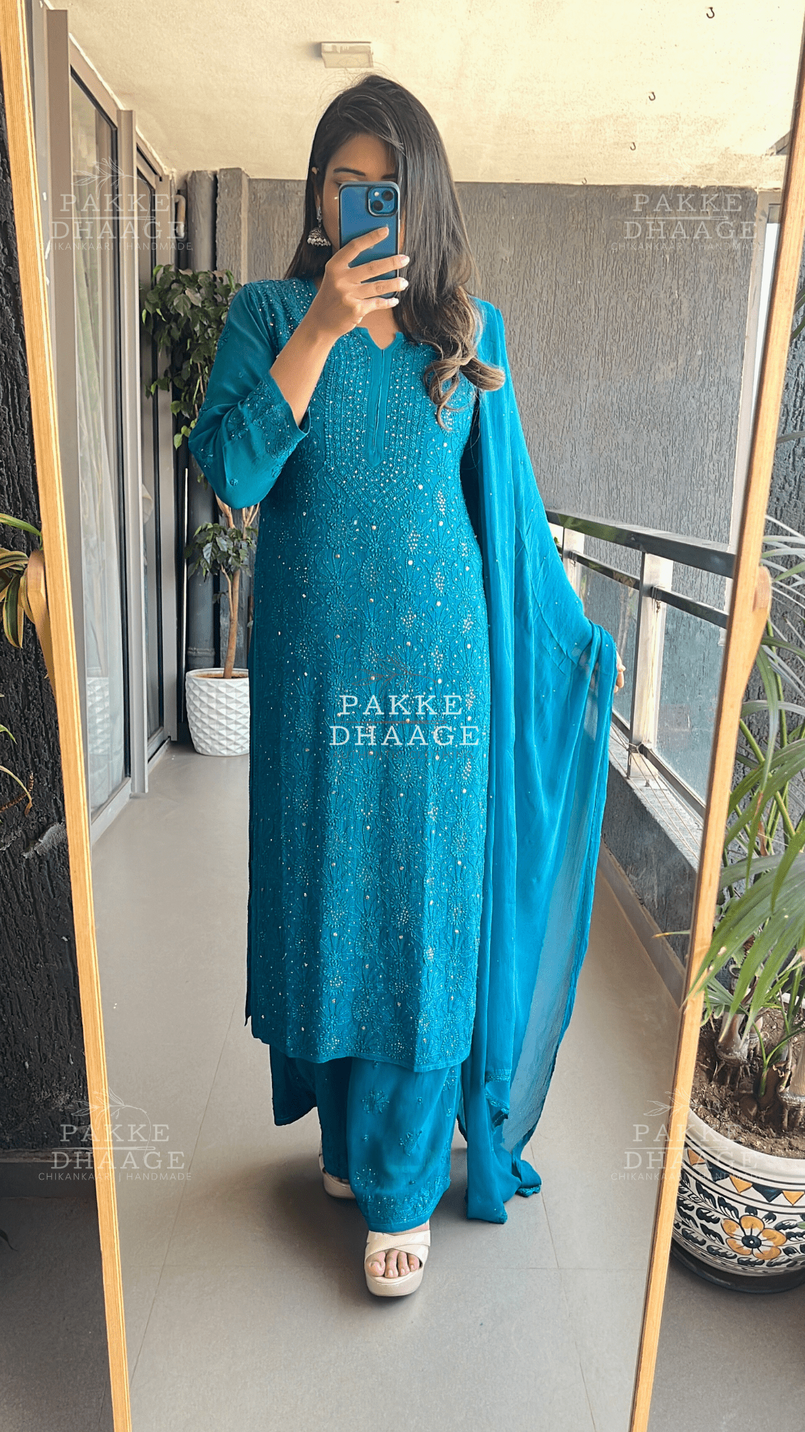 Person wearing a teal chikankari embroidered outfit with a dupatta, standing in front of a mirror.