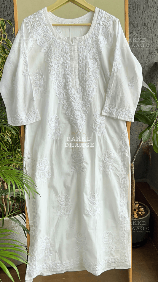 White chikankari embroidered kurta on a hanger with plants in the background