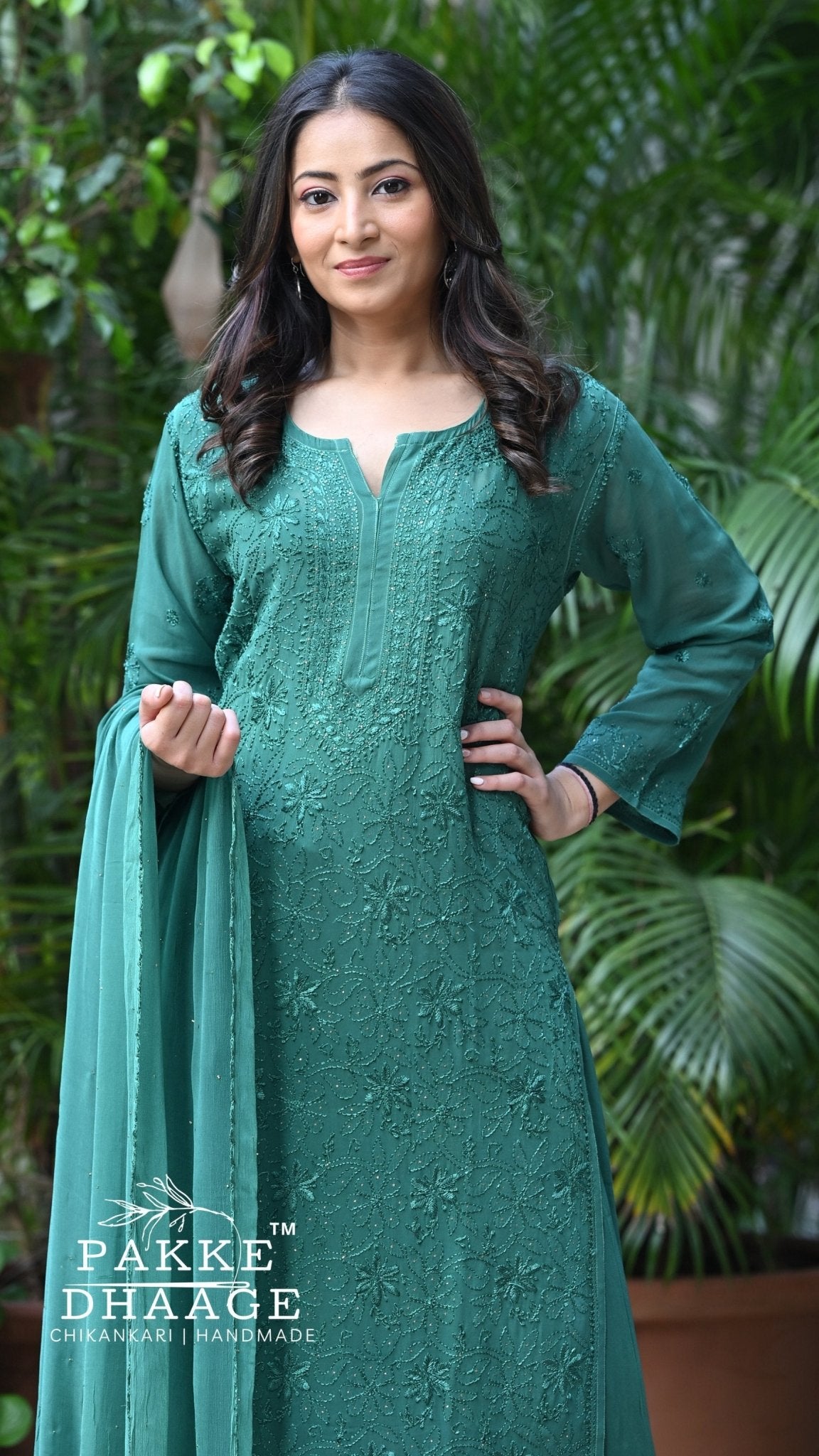 Woman wearing a green chikankari embroidered outfit with 'Pakke Dhaage' branding in an outdoor setting.