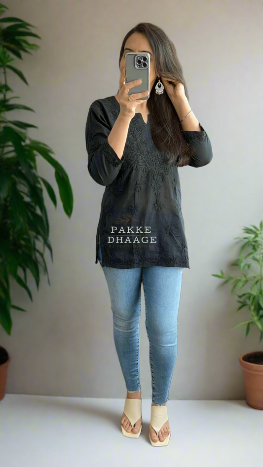Woman wearing a black chikankari short top with a light blue jeans.