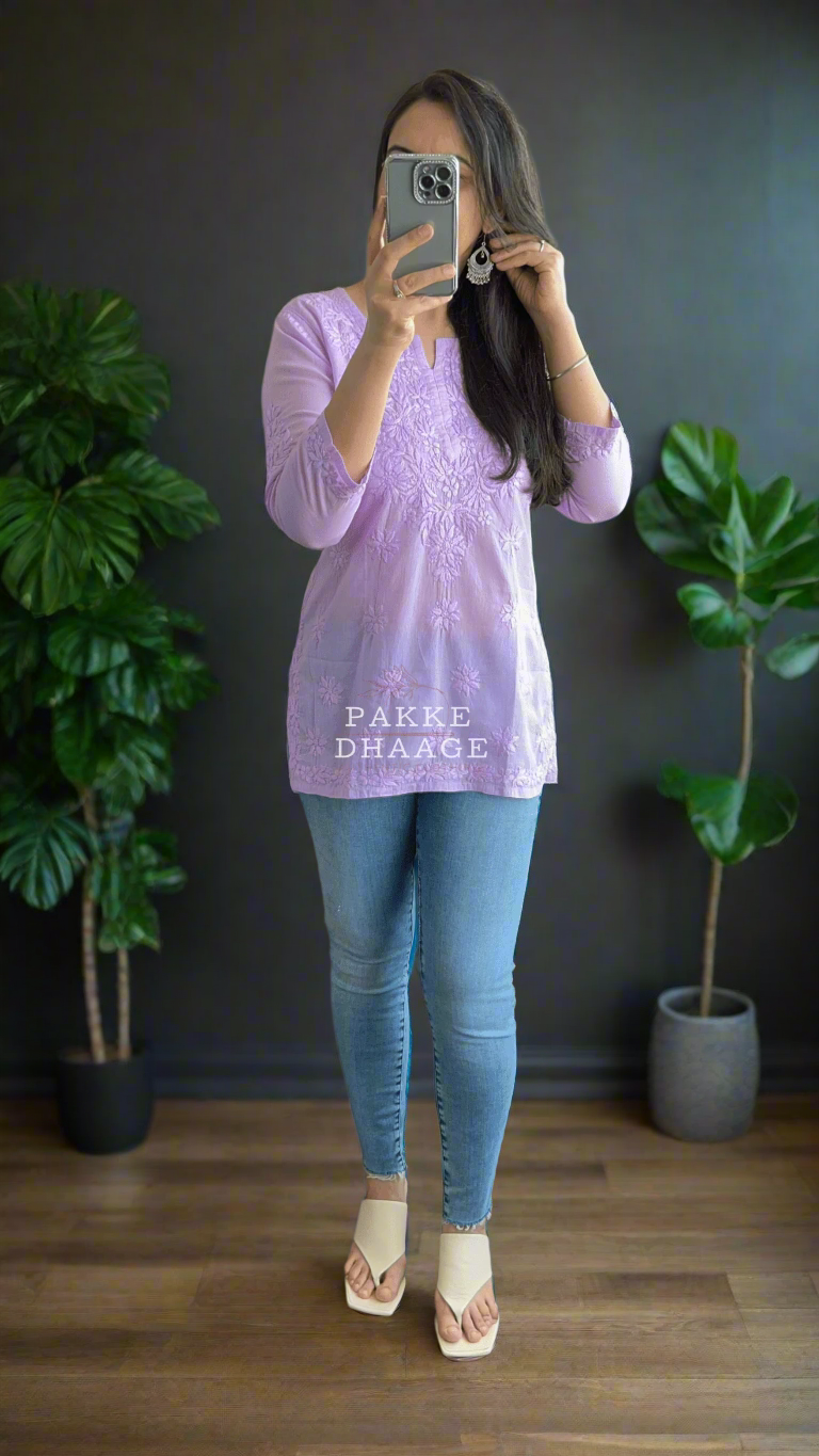 Person wearing a light purple chikankari top and blue jeans taking a mirror selfie.