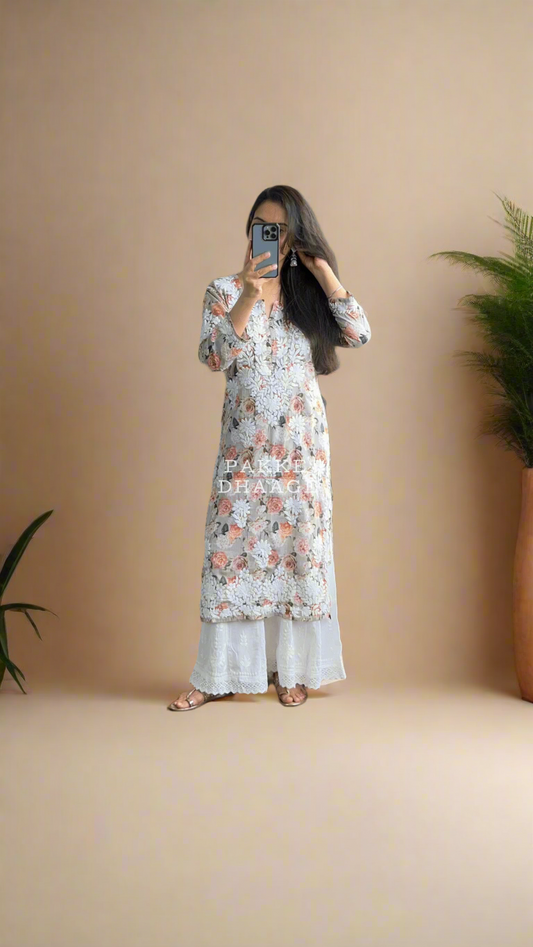 Woman a floral printed chikankari dress in a room with plants.