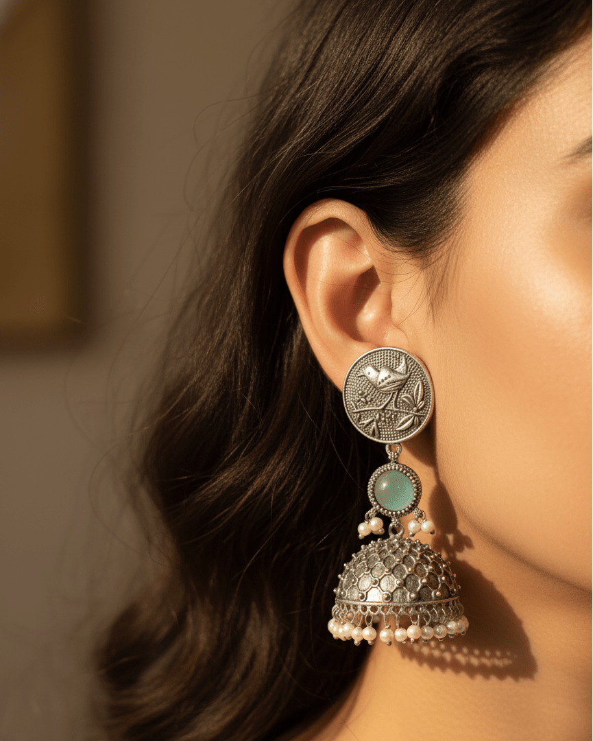 Close-up of a woman wearing a silver and turquoise earring with pearl accents.