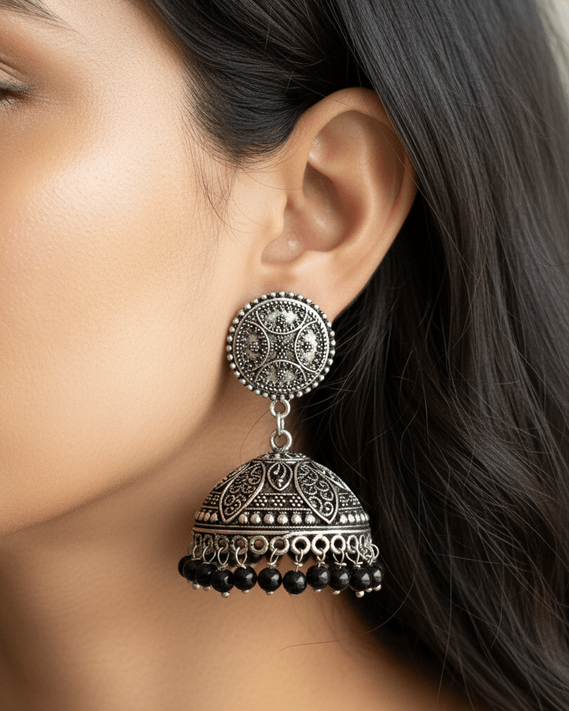 Close-up of a woman wearing an ornate oxidised silver earring with black beads.