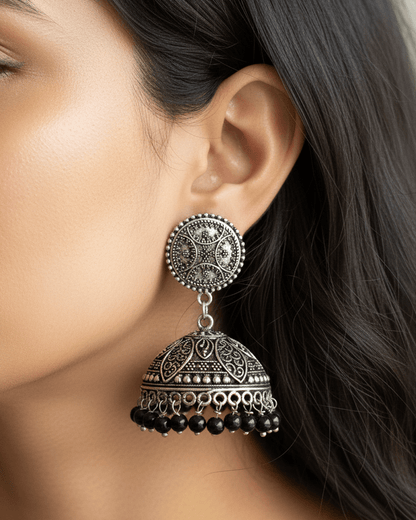 Close-up of a woman wearing an ornate oxidised silver earring with black beads.