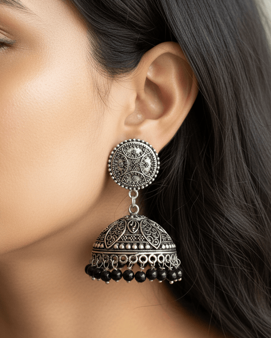 Close-up of a woman wearing an ornate oxidised silver earring with black beads.