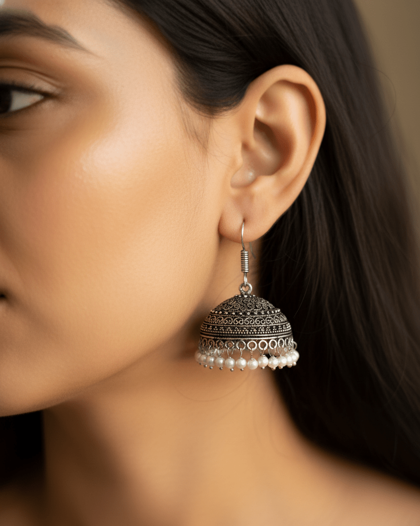 Close-up of a woman wearing a traditional oxidised silver earring with pearls.