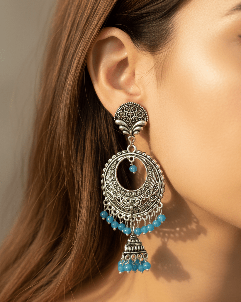 Close-up of a woman wearing an ornate oxidized silver earring with blue beads.