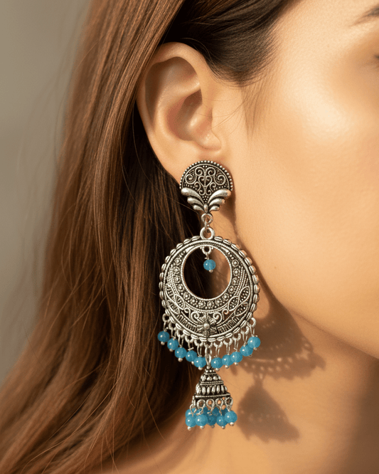 Close-up of a woman wearing an ornate oxidized silver earring with blue beads.