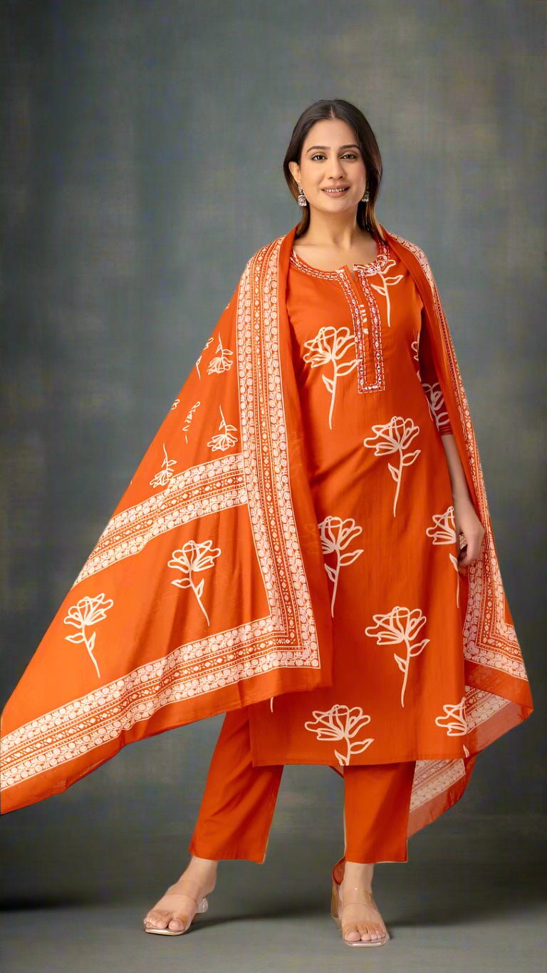 Woman wearing an orange traditional outfit with white patterns, standing against a plain background.