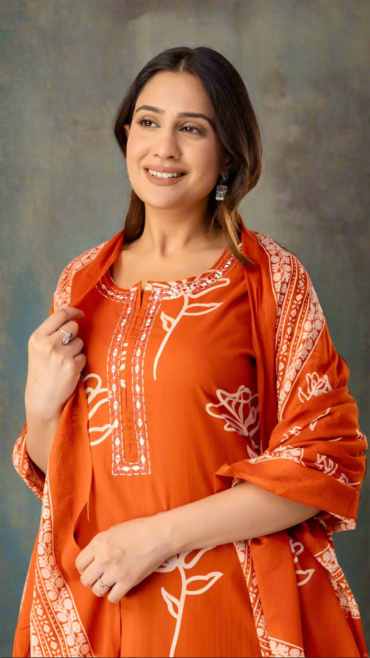 Woman wearing an orange traditional outfit with white patterns against a plain background