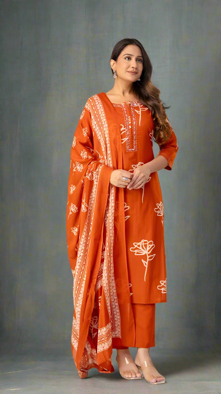 Woman wearing an orange traditional outfit with white patterns against a plain background