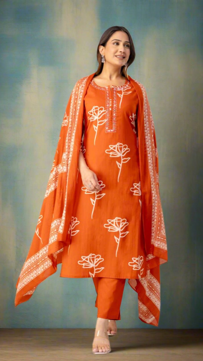 Woman wearing an orange traditional outfit with white floral patterns in a minimalistic setting.