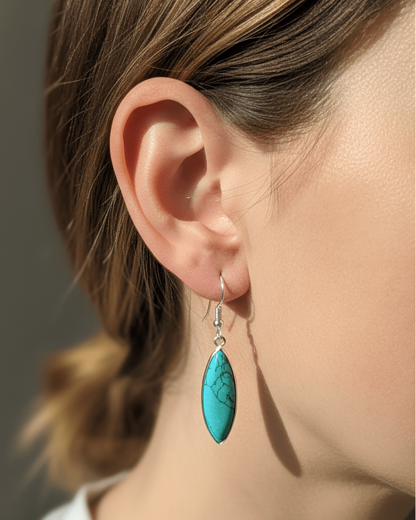 Close-up of a person wearing turquoise earrings with a neutral background