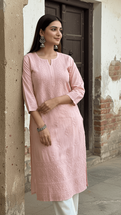 Woman wearing a mocha chikankari kurta standing against a textured wall.